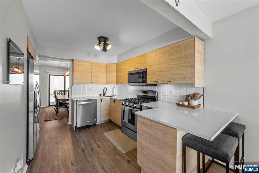 23 Bayowski Road, Unit 149 West Orange, NJ 07052 - Photo 4 of 38 a kitchen with a refrigerator a stove top oven a sink dishwasher and wooden cabinets with wooden floor