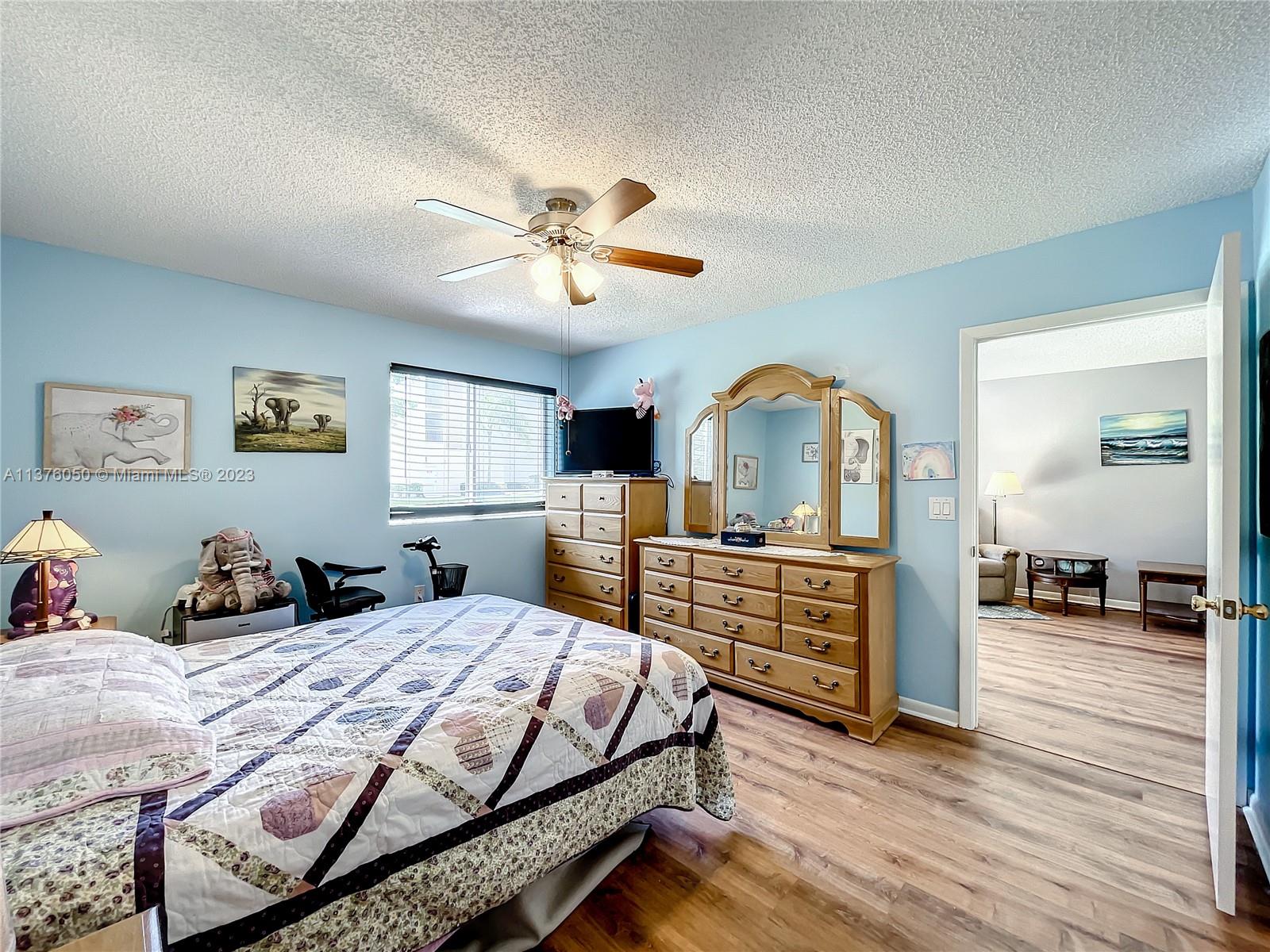 9580 Weldon Circle, Unit K110 Tamarac, FL 33321 - Photo 20 of 37 a bedroom with a bed a dresser and wooden floor