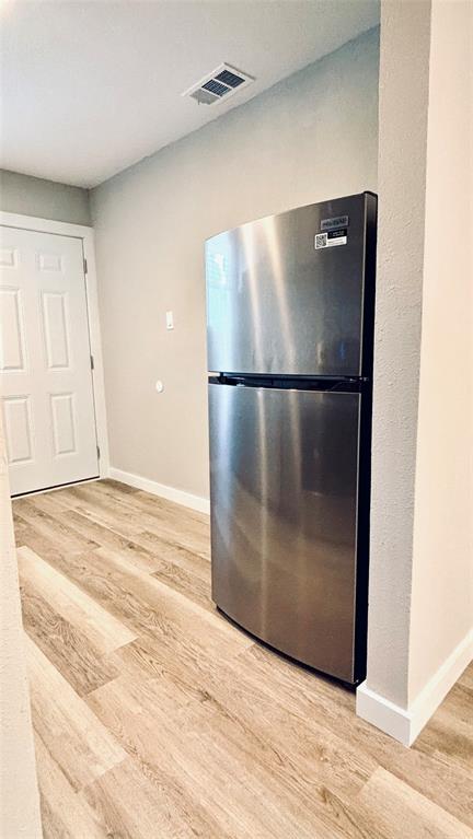 4603 Junius Street, Unit 9 Dallas, TX 75246 - Photo 3 of 9 a view of a refrigerator in kitchen and an empty room with wooden floor