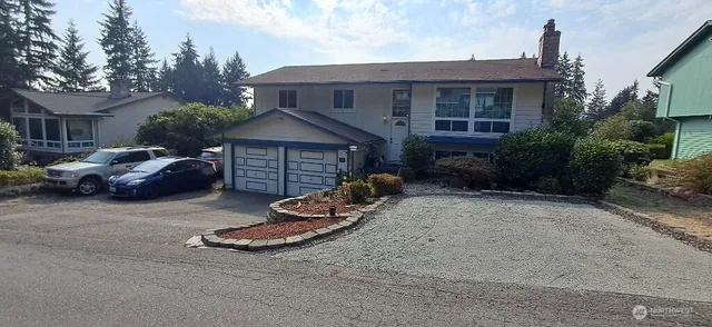 a front view of a house with yard and parking