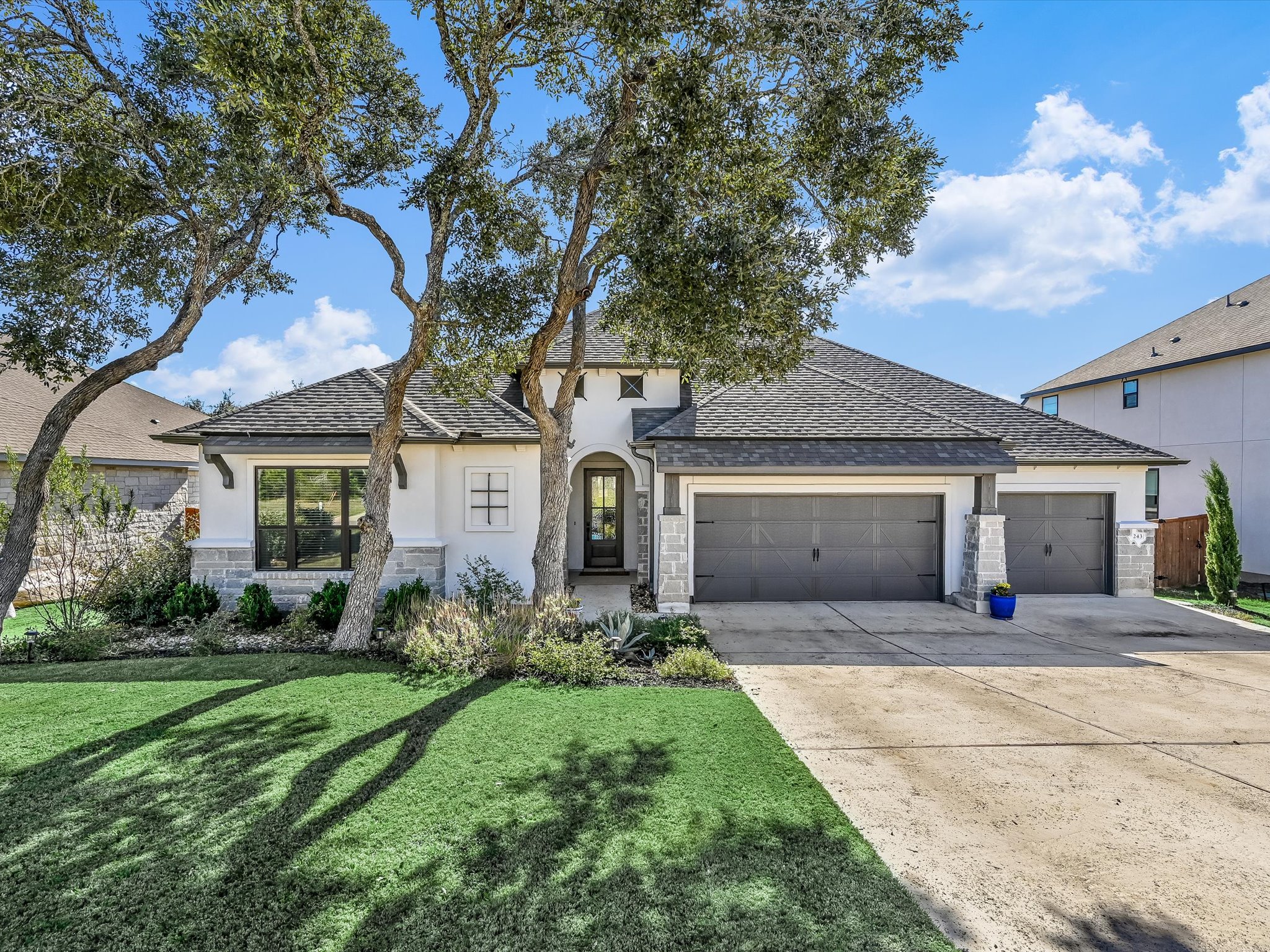 243 Bridge Water Loop Dripping Springs, TX 78620 - Photo 1 of 1 French country home with stucco siding, an attached garage, driveway, stone siding, and roof with shingles
