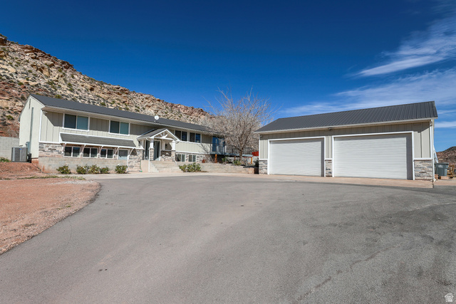 422 West Buckeye Reef Road Leeds, UT 84746 - Photo 1 of 47 View of front of home with stone siding, board and batten siding, an outbuilding, a detached garage, and a mountain view