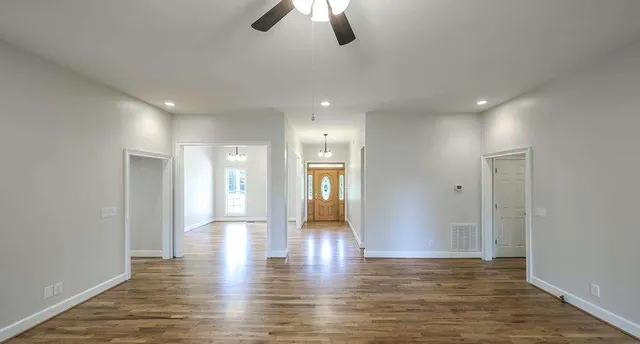 a view of an empty room with window and wooden floor