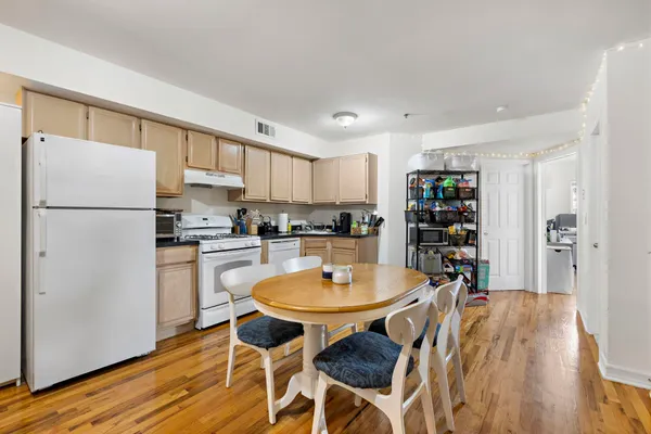 a kitchen with stainless steel appliances a dining table chairs and wooden floor