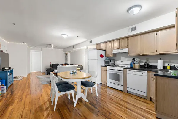 a kitchen with stainless steel appliances kitchen island granite countertop a white cabinets and chairs