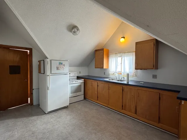 a large kitchen with a sink and dishwasher a stove top oven with wooden floor