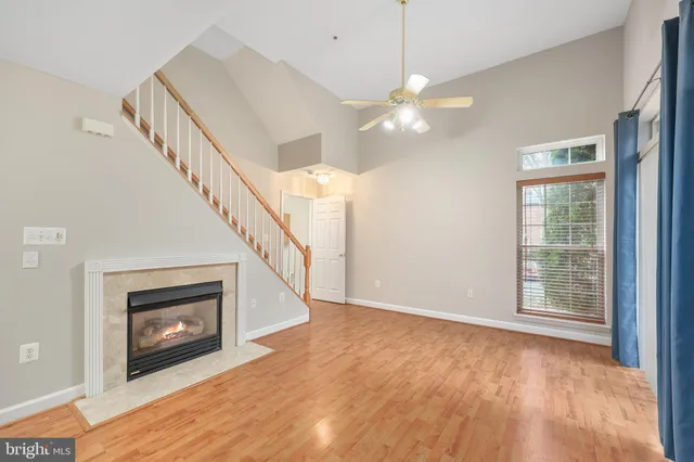 a view of an empty room with wooden floor fireplace and a window