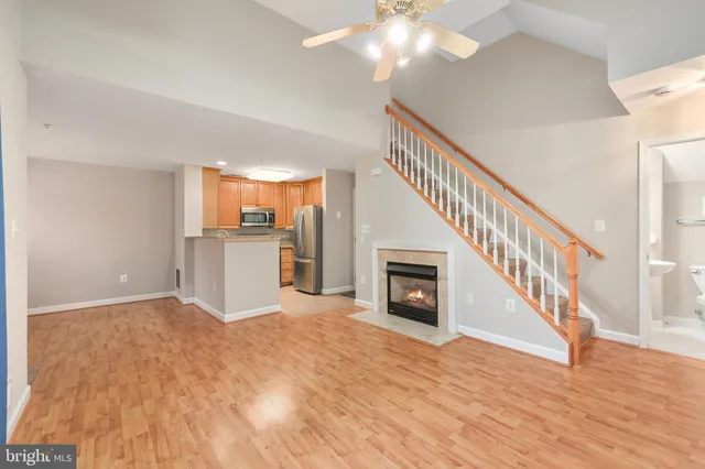 a view of a livingroom with wooden floor kitchen view and a fireplace