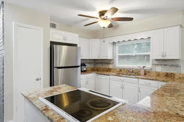a kitchen with stainless steel appliances granite countertop a sink a refrigerator and a granite counter tops