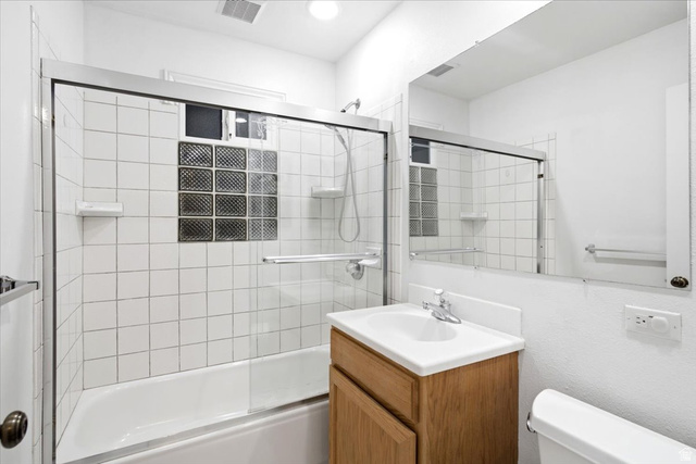 1341 29th Street Ogden, UT 84403 - Photo 21 of 37 Bathroom featuring a built-in bathtub with shower, glass enclosure, white square tile surround, and a glass block window
