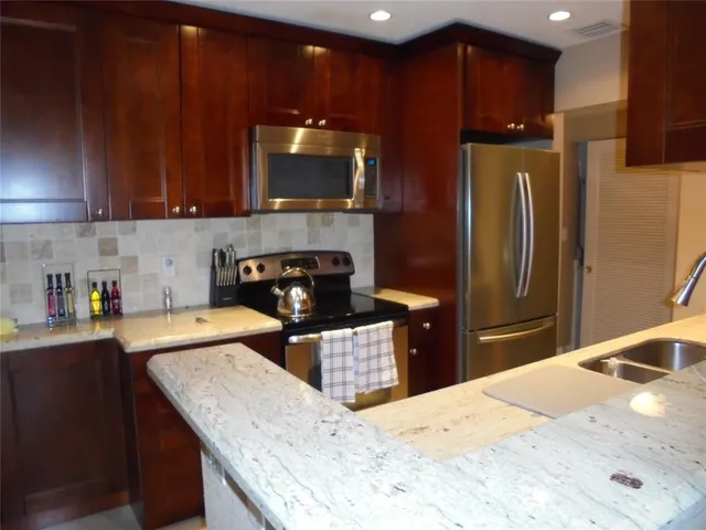 a kitchen with stainless steel appliances wooden cabinets a sink and a stove