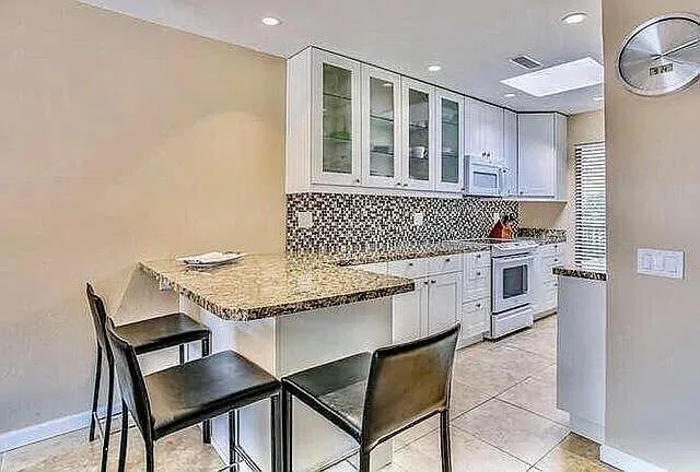 a kitchen with granite countertop a stove a sink and a refrigerator
