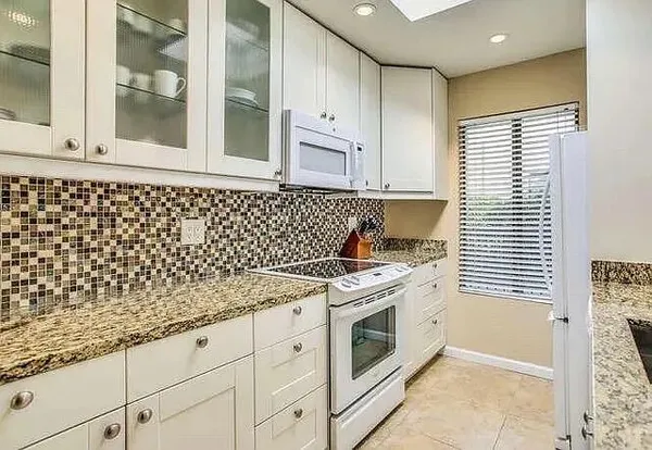 a kitchen with granite countertop white cabinets and white appliances