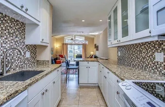 a kitchen with granite countertop a sink stove and cabinets