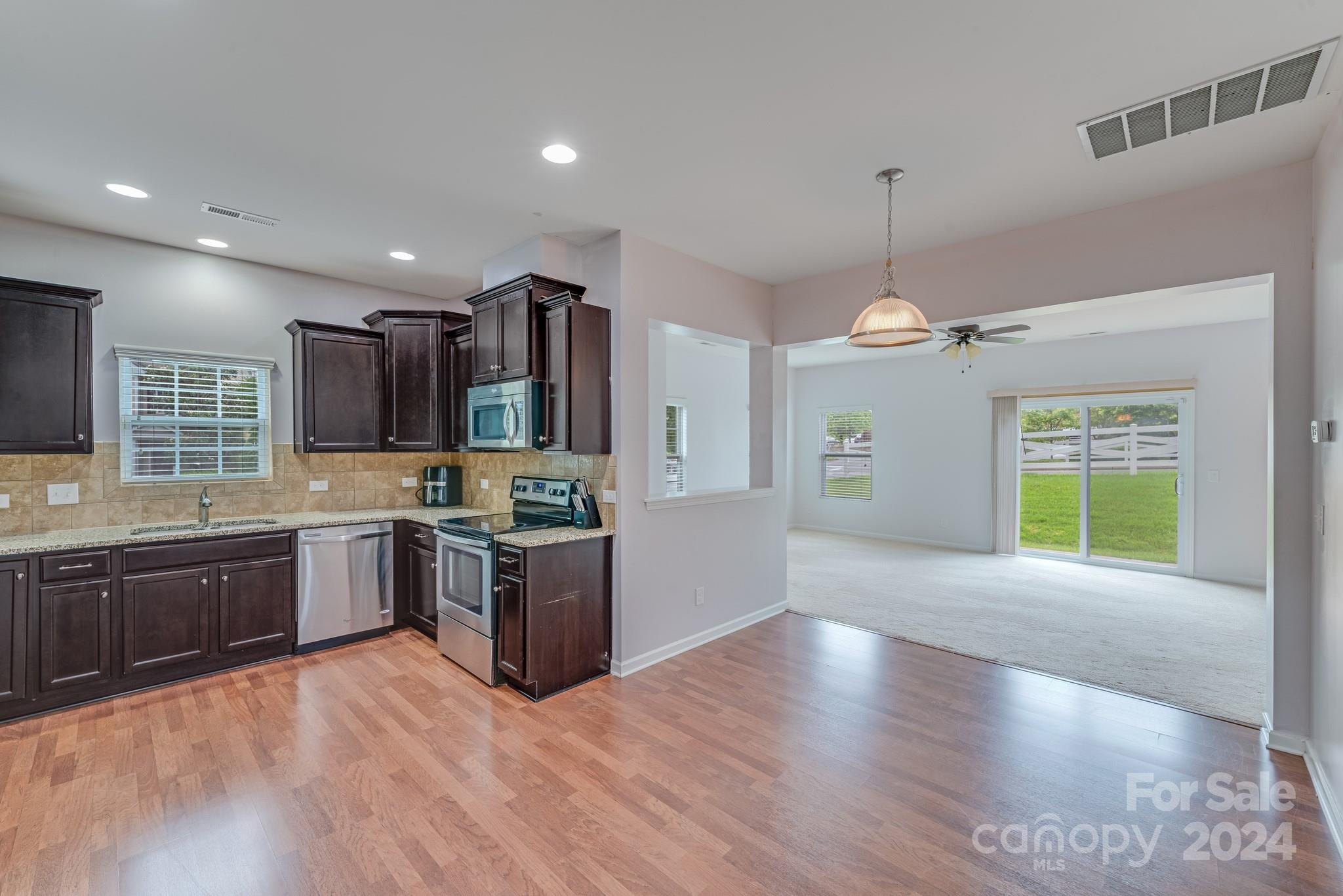 a large kitchen with granite countertop a large center island a sink stainless steel appliances and cabinets