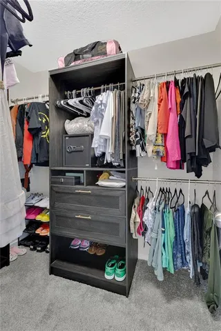 a view of walk in closet with clothes and shoes