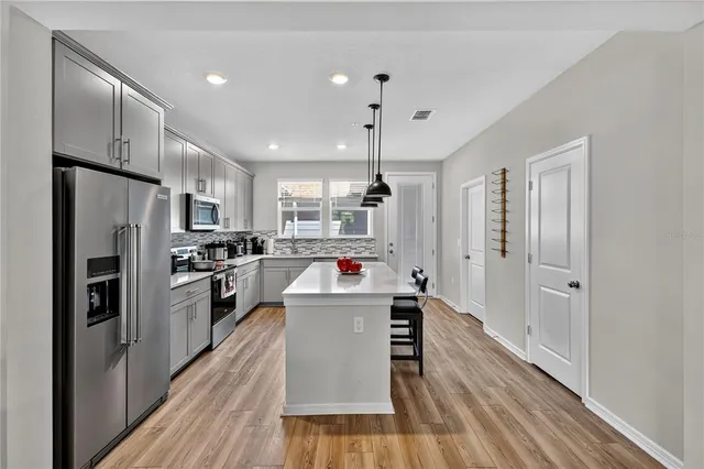 a kitchen view with wooden floor and stainless steel appliances