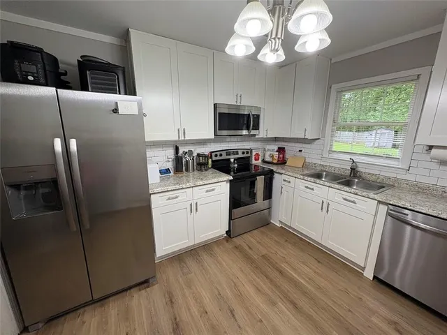 a kitchen with stainless steel appliances granite countertop a refrigerator a sink dishwasher a stove top oven a refrigerator with island and cabinets