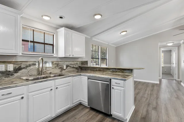 a kitchen with a sink cabinets wooden floor and stainless steel appliances