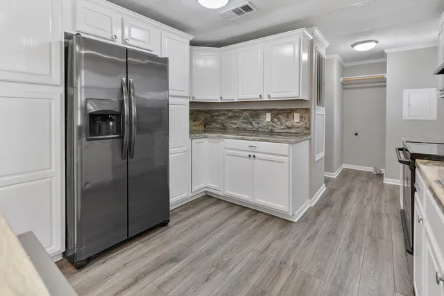 a kitchen with a refrigerator a stove and wooden floor