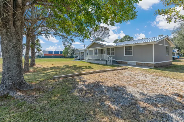 a view of a house with a yard and large tree