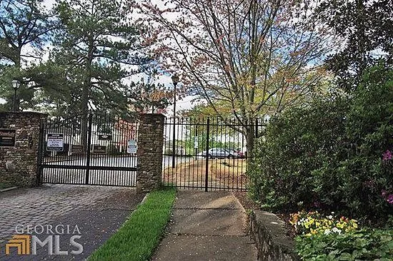 a view of a white house with a large tree and wooden fence