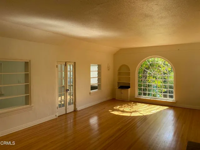 an empty room with wooden floor fan and windows