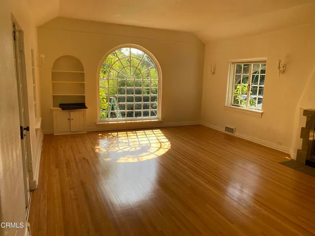 a view of an empty room with a window and wooden floor