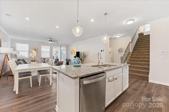 a kitchen with stainless steel appliances kitchen island granite countertop wooden floor and white cabinets