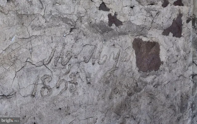 a view of a white house next to a yard with big trees