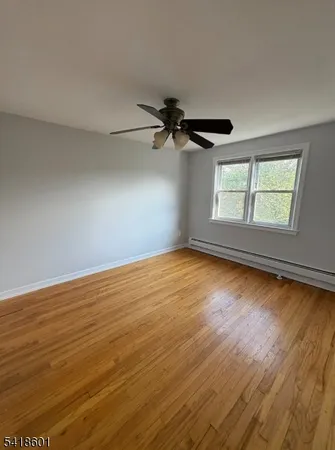 a view of empty room with wooden floor and fan