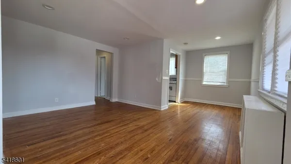 an empty room with wooden floor cabinet and windows