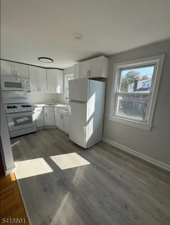 a kitchen with granite countertop white cabinets and white appliances