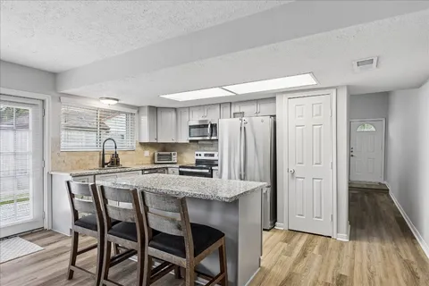 a kitchen with stainless steel appliances a dining table chairs refrigerator and sink
