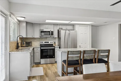 a kitchen with kitchen island granite countertop a stove top oven a sink dishwasher a dining table and chairs