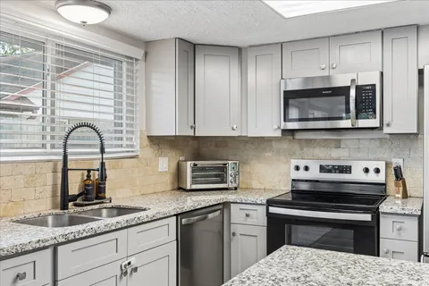 a kitchen with granite countertop a sink stainless steel appliances and cabinets