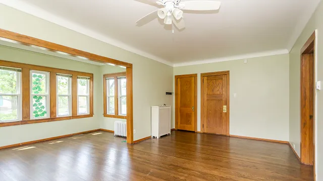 a view of an empty room with wooden floor and a window