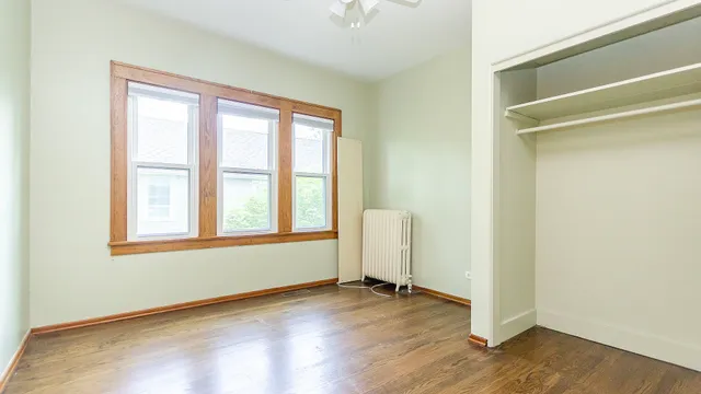 a view of an empty room with wooden floor and closet