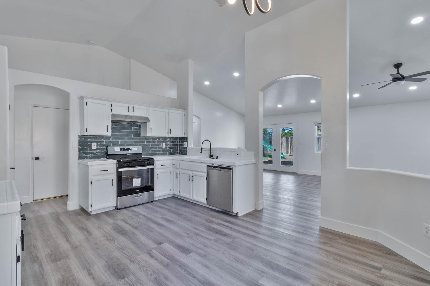 7110 Firebaugh Street Bakersfield, CA 93313 - Photo 7 of 37 a kitchen with granite countertop a stove top oven a sink dishwasher a refrigerator and a dining table with wooden floor