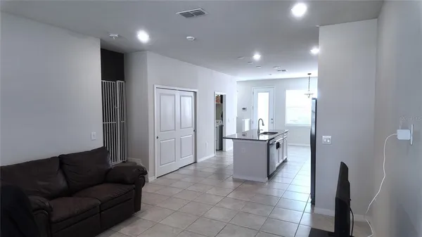 a living room with stainless steel appliances furniture a rug and a view of kitchen