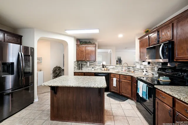 a large kitchen with granite countertop lots of counter top space and stainless steel appliances