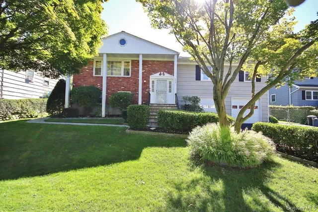 a front view of a house with a yard and trees