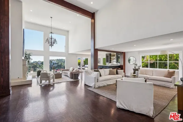 a living room with furniture large windows and wooden floor