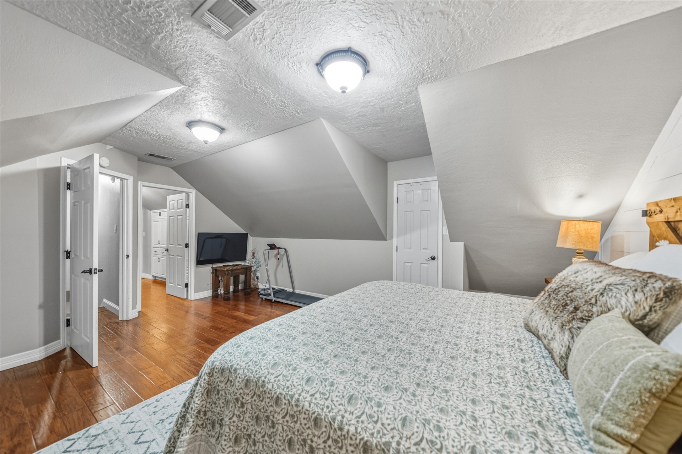 19989 Meadow Bend Road Hempstead, TX 77445 - Photo 19 of 35 Primary bedroom located upstairs offers generous floor space, wood flooring, and distinctive sloped ceilings that add architectural interest.