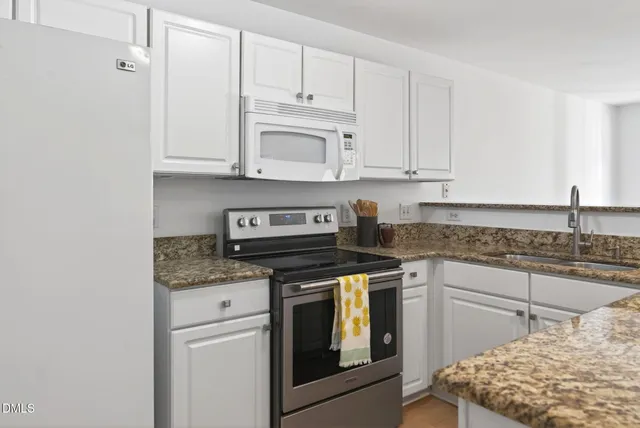 a kitchen with granite countertop white cabinets and white appliances