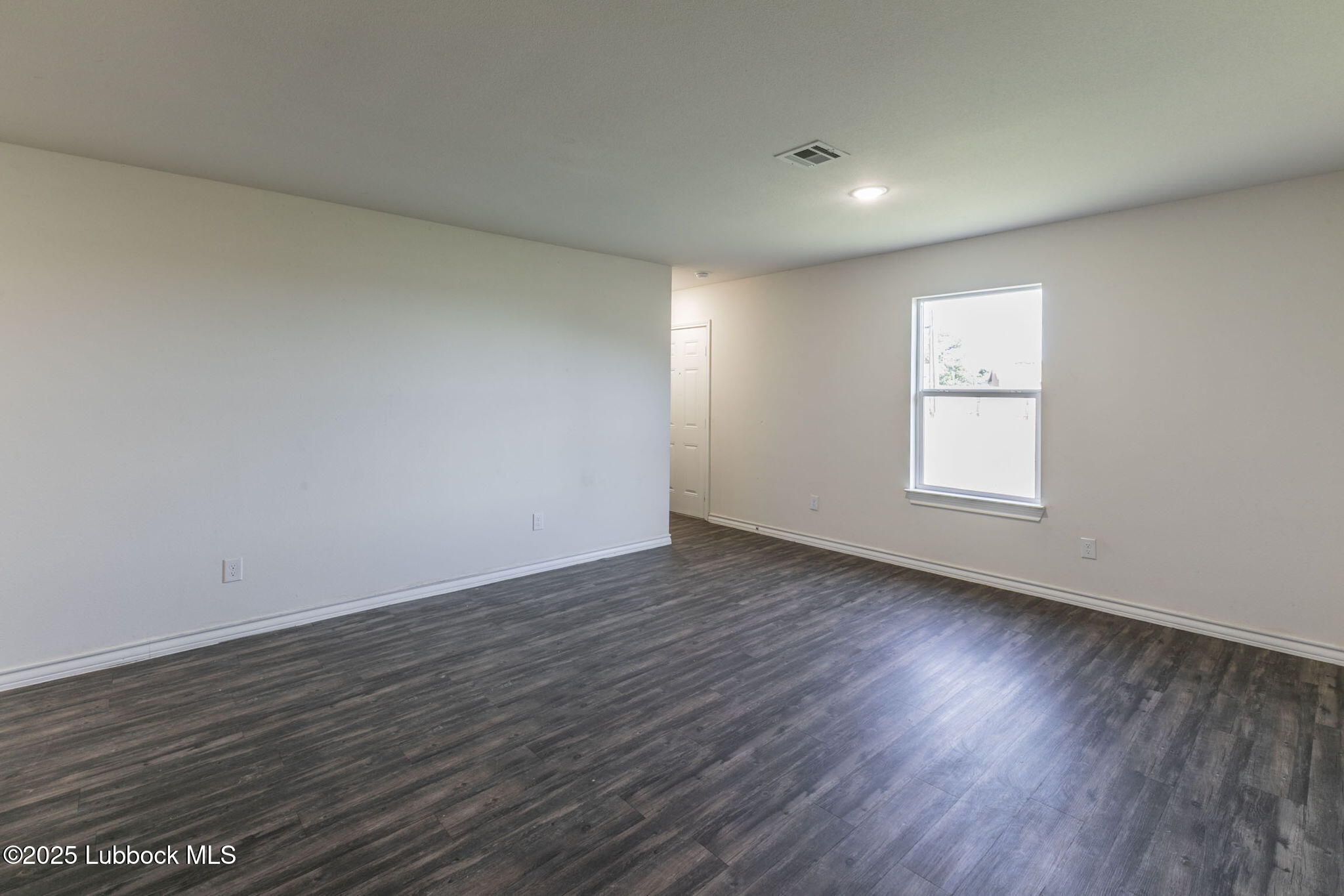 3511 East Colgate Street Lubbock, TX 79403 - Photo 2 of 18 an empty room with wooden floor and windows