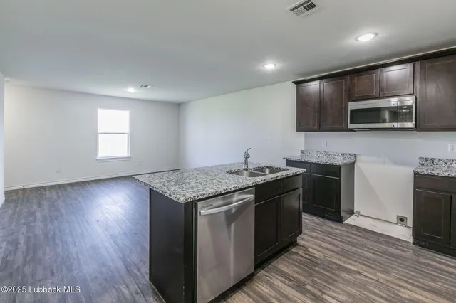 a kitchen with stainless steel appliances granite countertop a stove a sink and a microwave