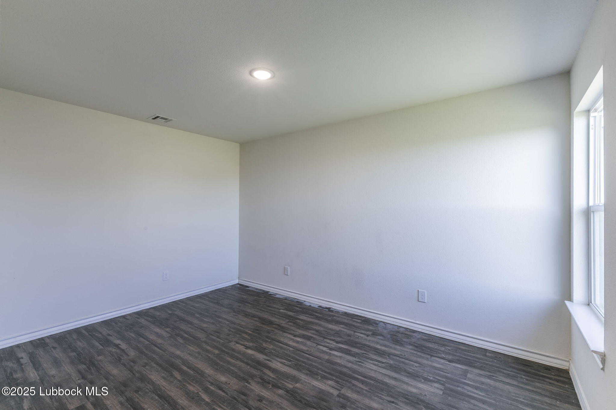 3511 East Colgate Street Lubbock, TX 79403 - Photo 6 of 18 a view of an empty room with wooden floor and a window