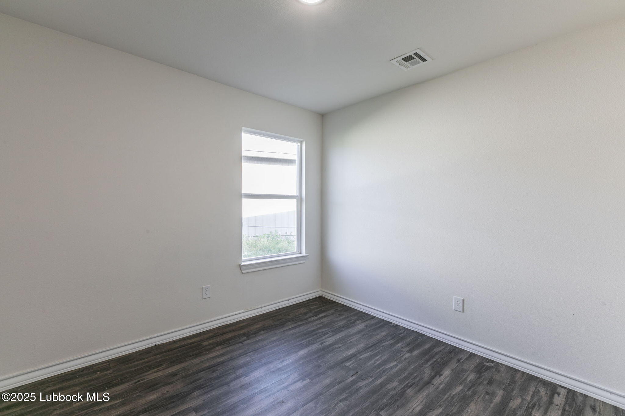 3511 East Colgate Street Lubbock, TX 79403 - Photo 10 of 18 an empty room with wooden floor and windows