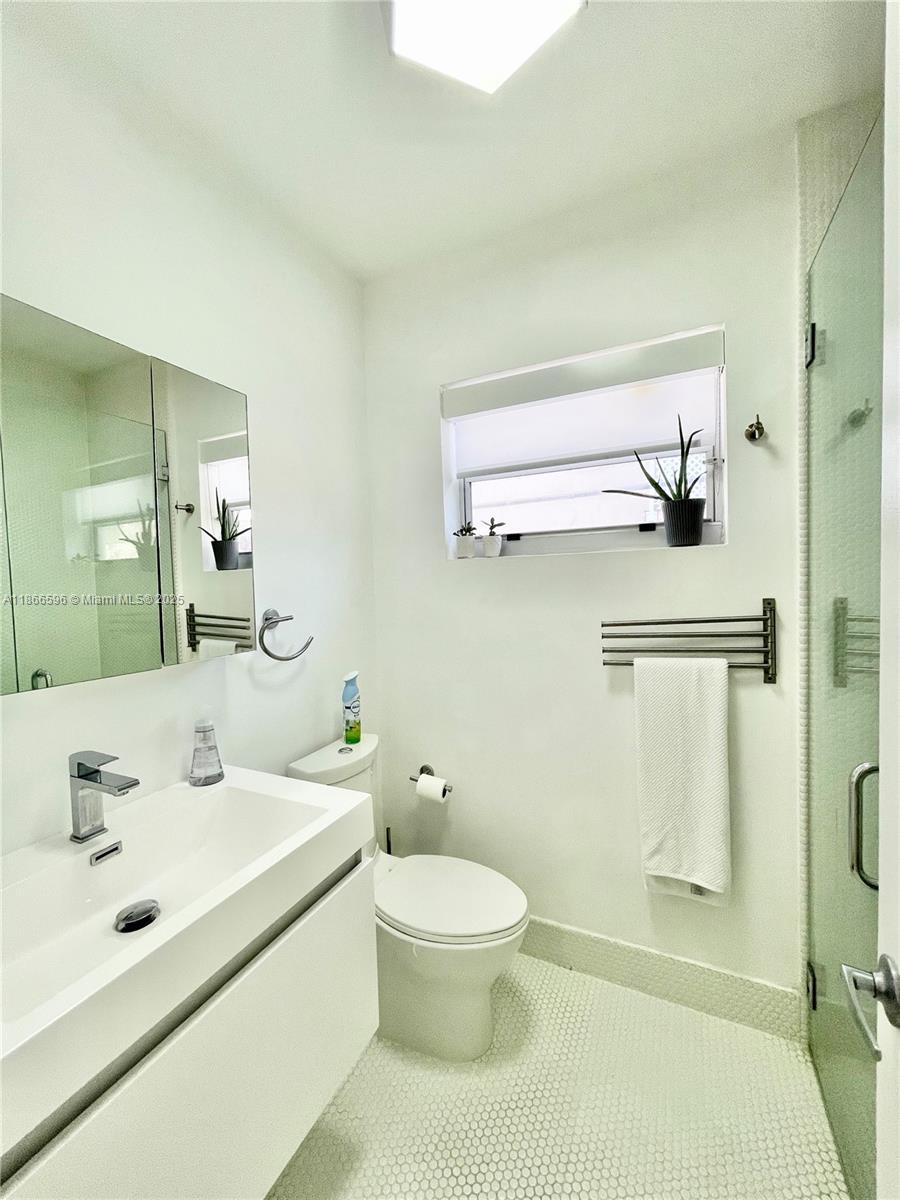 1604 Drexel Avenue, Unit 209 Miami Beach, FL 33139 - Photo 5 of 9 a bathroom with a sink a toilet and a mirror